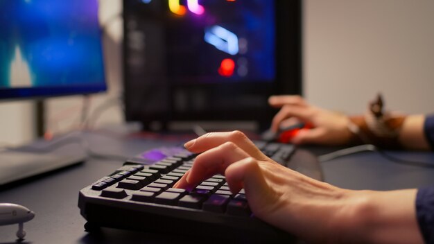 Close-up do jogador usando teclado e mouse RGB para competição online