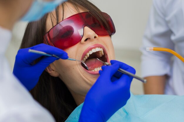 Close-up do paciente recebendo procedimento com dentistas