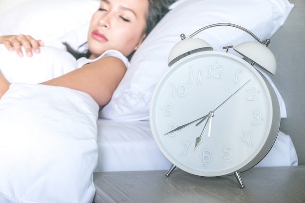 Close-up do relógio com sono da mulher em segundo plano