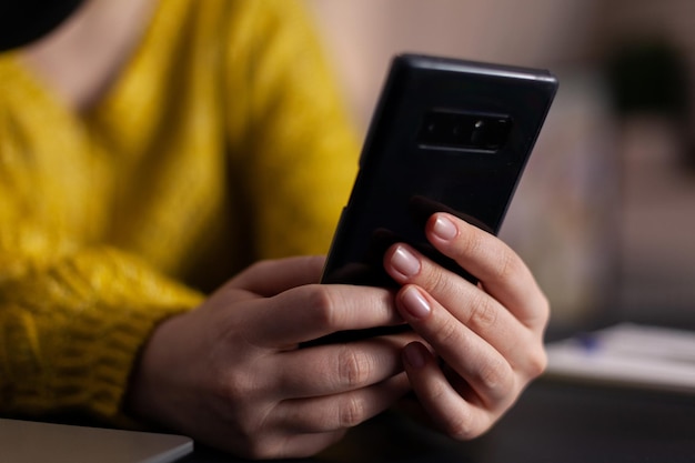 Foto grátis close-up do vlogger de mídia social com fone de ouvido segurando perguntas de leitura de smartphone respondendo usando microfone de produção sentado na mesa no estúdio de podcasting em casa. show no ar