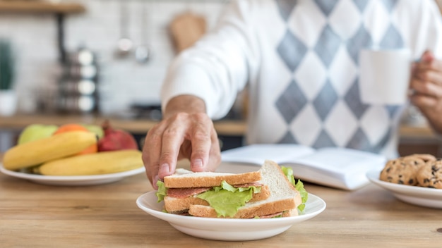 Close-up homem comendo sanduíches saudáveis na cozinha