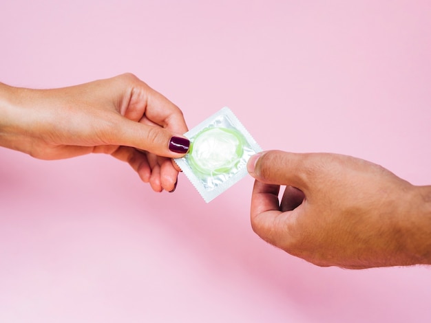 Close-up homem e mulher segurando um preservativo verde