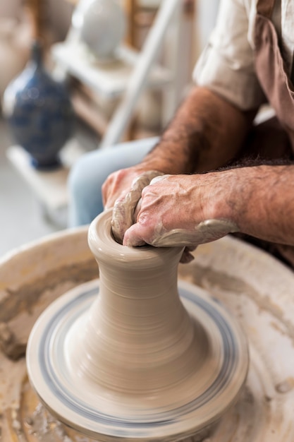 Close-up homem fazendo cerâmica dentro de casa