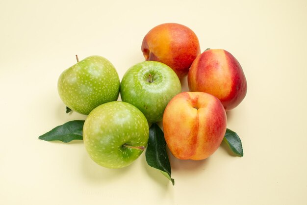Close-up lateral de maçãs e nectarinas, três nectarinas e três maçãs com folhas verdes