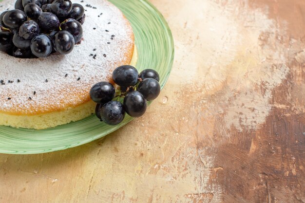 Close-up lateral de um bolo um bolo apetitoso com cachos de uvas com açúcar em pó no prato