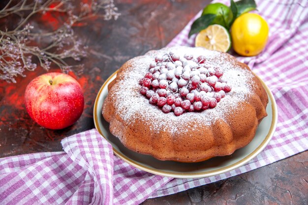 Close-up lateral de um bolo um bolo com frutas cítricas de groselha na toalha de mesa quadriculada maçã