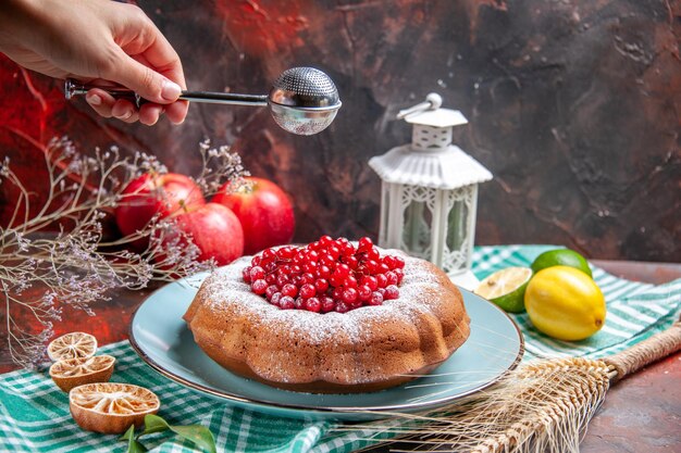 Close-up lateral ver um bolo um bolo com frutas e limões na toalha de mesa colher maçãs na mão