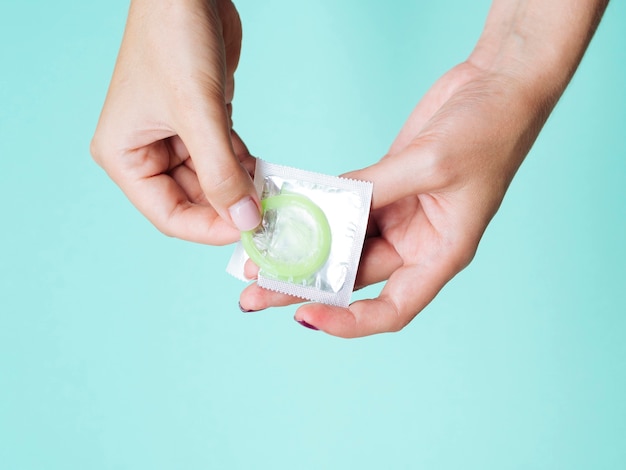 Close-up mulher desembrulhar um preservativo verde