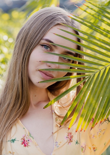 Foto grátis close-up mulher olhando através da folha da planta