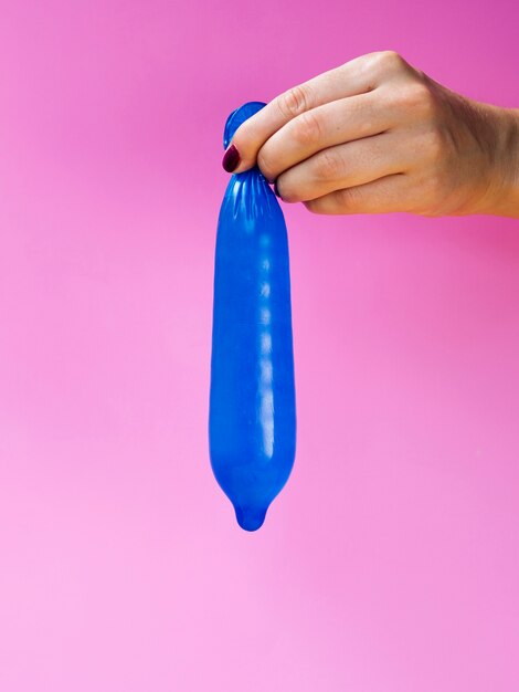 Close-up mulher segurando um preservativo azul cheio
