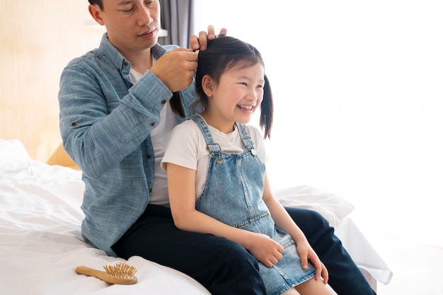 Foto grátis close-up pai amarrando o cabelo da menina