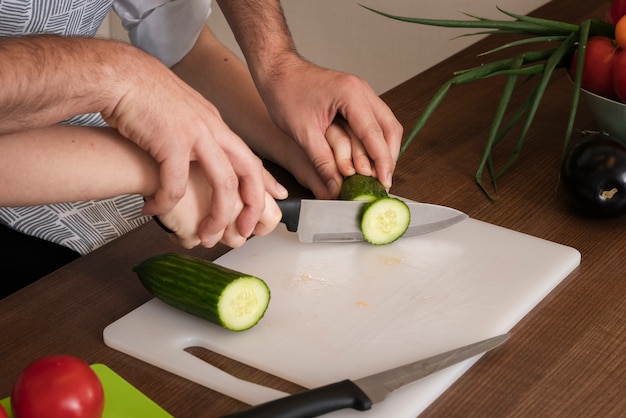 Close-up pai ensinando filho a cortar legumes