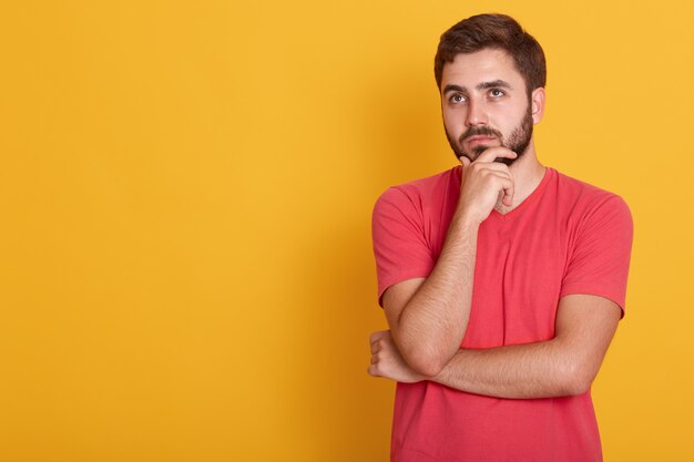 Close-up retrato de forte cara confiante, segurando sua mão sob o queixo, estúdio, tiro, deixe-me pensar, macho usa camiseta casual vermelha