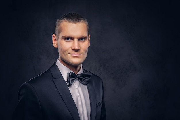 Close-up, um retrato de um homem bonito e elegante em um elegante terno preto sobre um fundo escuro.