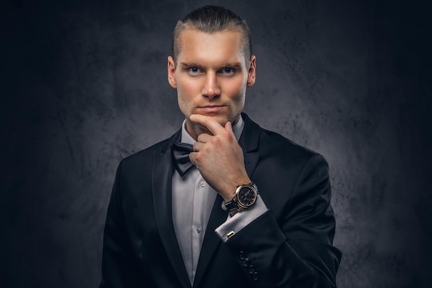 Close-up, um retrato de um homem bonito e elegante em um elegante terno preto sobre um fundo escuro.