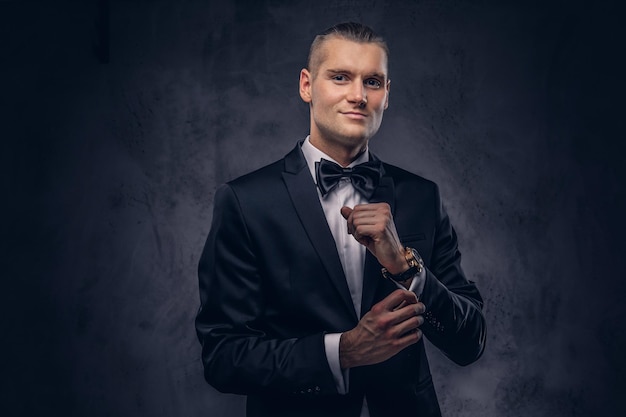 Close-up, um retrato de um homem bonito e elegante em um elegante terno preto sobre um fundo escuro.