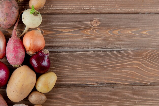 Close-up vista de legumes como batata de cebola rabanete em fundo de madeira com espaço de cópia