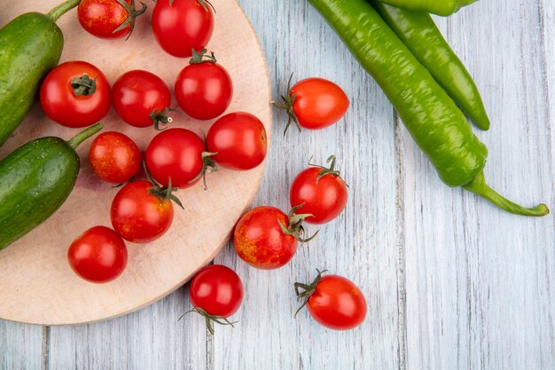 Close-up vista de legumes como pepino e tomate na tábua com pimenta na parede de madeira