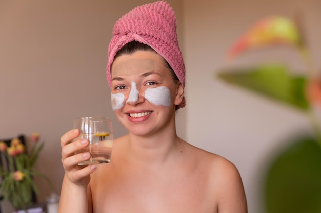 Close-up vista de mulher feliz com máscara no rosto em casa com água de vidro