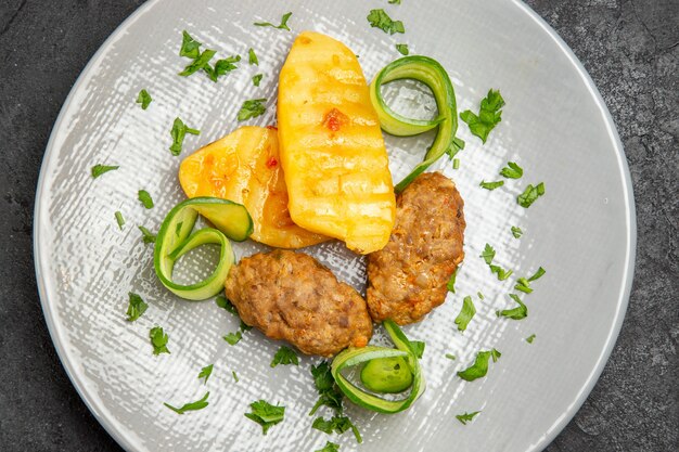 Foto grátis close-up vista de um jantar saboroso com batata costeleta em um prato branco na mesa escura