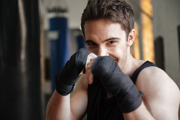 Close-up vista do boxeador sorridente fazendo exercício no ginásio