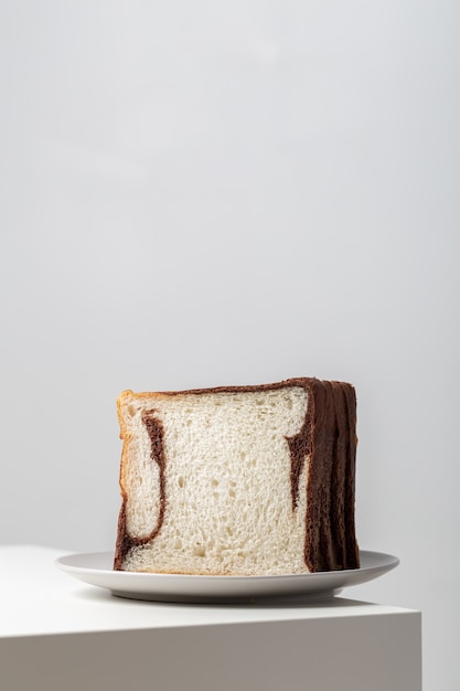 Close vertical de fatias de pão branco misturadas com chocolate em um prato sobre a mesa sob as luzes