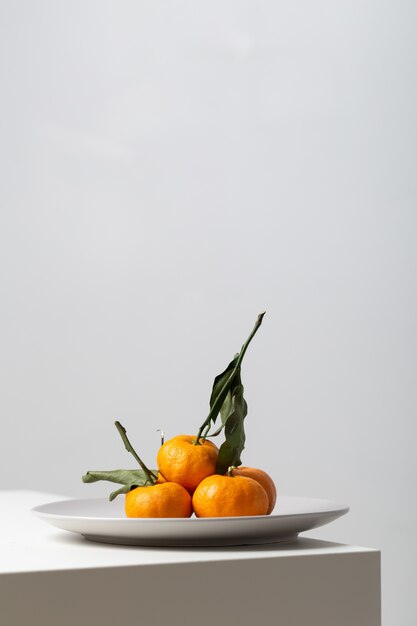 Close vertical de tangerinas em um prato sobre a mesa sob as luzes em branco