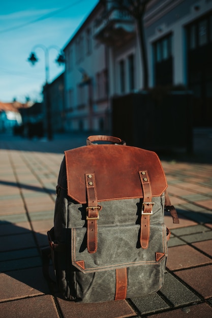 Close vertical de uma mochila cinza e marrom no chão na rua