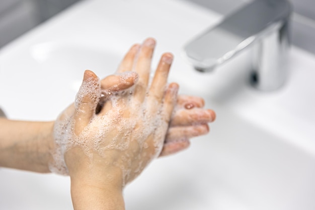 Closeup a criança lava as mãos no banheiro