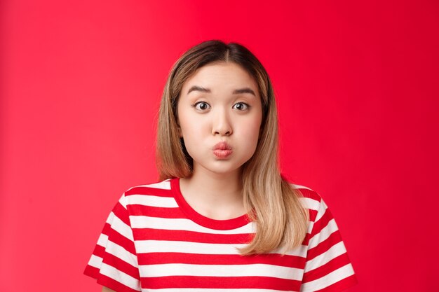 Closeup boba linda garota loira asiática fazendo beicinho fazendo rosto brincalhão dobrar os lábios prender a respiração ficar vermelho de volta ...