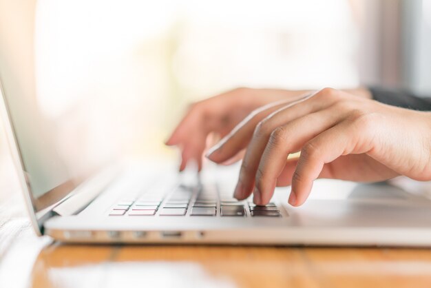 Closeup da mão da mulher de negócio que datilografa no teclado do portátil.