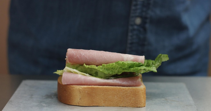 Foto grátis closeup da mão do homem fazendo sanduíche coloca dos lados todos os ingredientes no prato