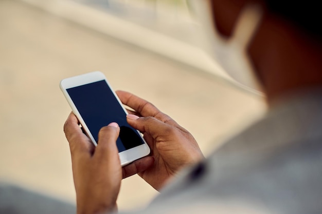 Closeup de empresária afro-americana mandando mensagens no celular ao ar livre