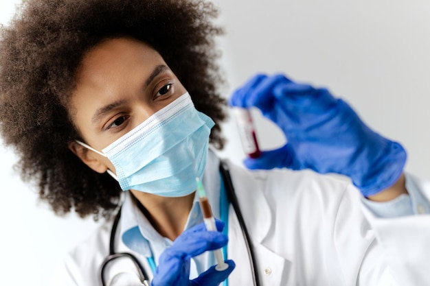 Closeup de epidemiologista segurando vacina e amostra de exame de sangue no hospital