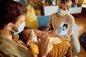 Foto grátis closeup de família cumprimentando seu médico durante videochamada devido à pandemia de coronavírus