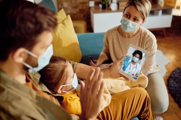 Closeup de família cumprimentando seu médico durante videochamada devido à pandemia de coronavírus