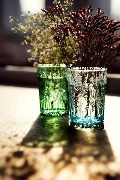 Closeup de flores em vasos de vidro na mesa de madeira