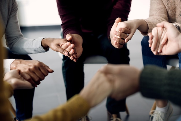 Closeup de grupo de pessoas de mãos dadas durante a sessão de psicoterapia