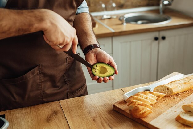 Closeup de homem descascando abacate enquanto prepara comida na cozinha