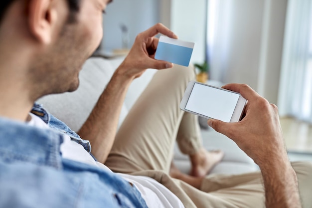 Foto grátis closeup de homem usando telefone inteligente e cartão de crédito para compras on-line em casa copiar espaço