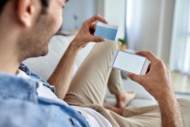 Closeup de homem usando telefone inteligente e cartão de crédito para compras on-line em casa Copiar espaço