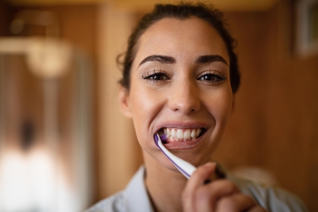 Closeup de linda mulher escovando os dentes no banheiro