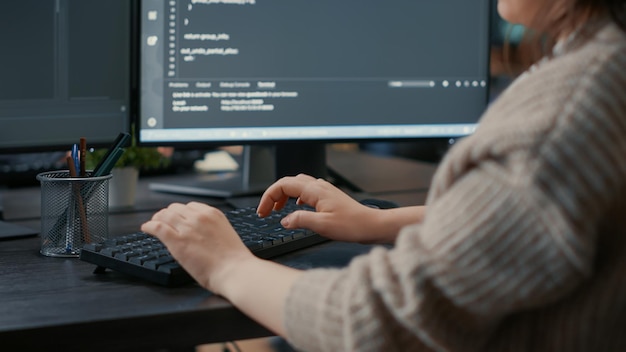 Foto grátis closeup de mãos de codificador de software caucasiano digitando no teclado na frente de telas de computador com interface de programação. desenvolvedor de banco de dados sentado na mesa escrevendo algoritmo para agência de ti.