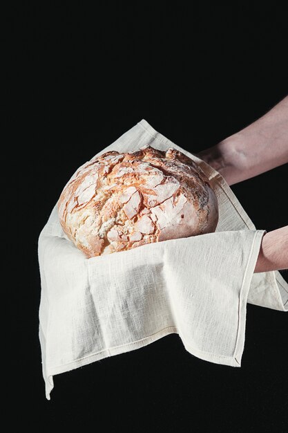 Closeup de mãos masculinas colocar pão fresco no preto