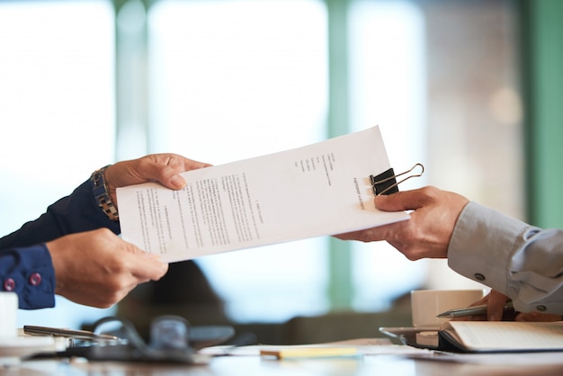 Closeup de mãos passando o contrato ao empresário irreconhecível