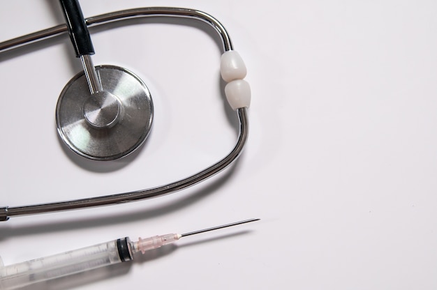 Closeup de medicamentos, seringas e estetoscópio. Imagem de cuidados de saúde limpa e brilhante. Seringa de plástico com agulha isolada no fundo branco