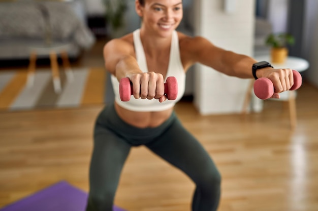 Closeup de mulher atlética praticando com peso de mãos na sala de estar