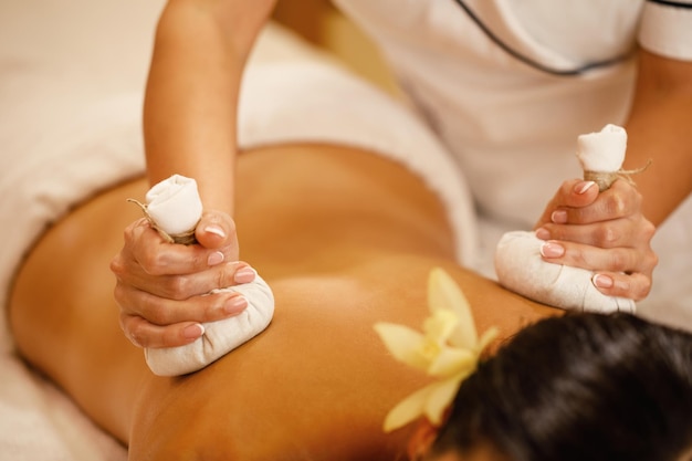 Foto grátis closeup de mulher recebendo massagem de volta com compressas de ervas de desintoxicação no salão spa