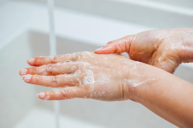 Closeup de mulher usando sabão enquanto hash as mãos no banheiro