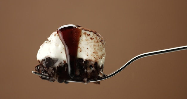 Foto grátis closeup de pedaço de bolo de chocolate em um garfo com cobertura líquida